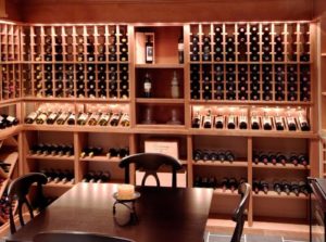 A bespoke wine room with custom lighting and light tone wood shelving