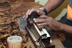 Up close photo of a hand-rolled cigar being made on a worktable.